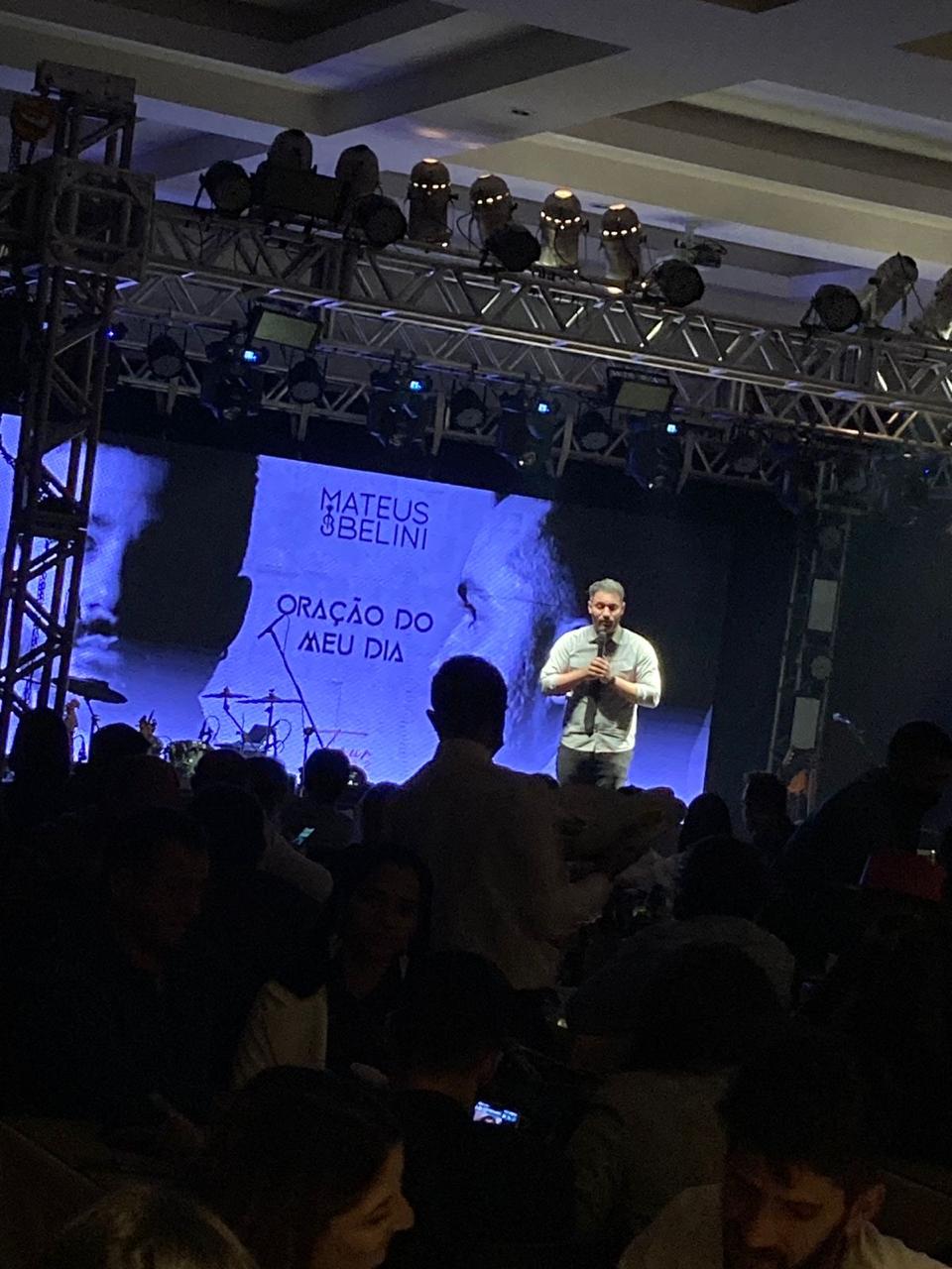 Visão ampla do salão do mesmo evento corporativo, com centenas de convidados nas mesas